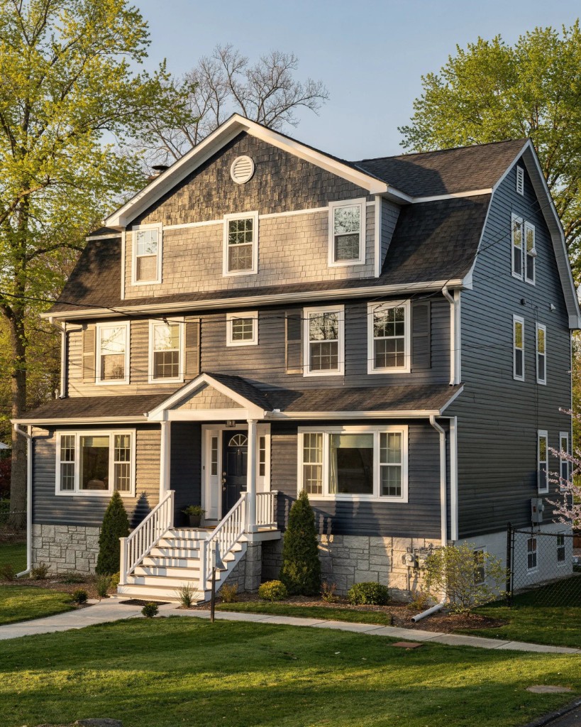 Dutch Colonial with navy lap siding, grey shake gambrel peaks, and stone veneer base in Central NJ