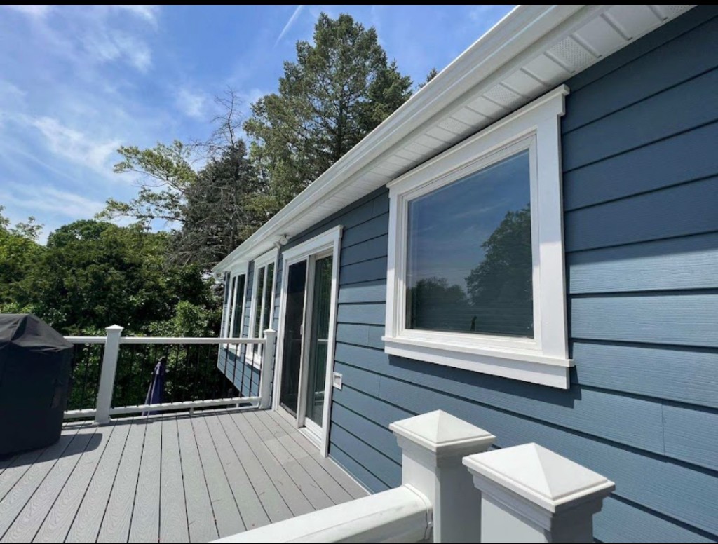 Trim surrounds at a window and sliding patio door on blue-gray vinyl siding, North Jersey